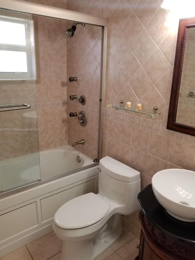 full bathroom featuring tile walls, bath / shower combo with glass door, vanity, tile patterned floors, and toilet