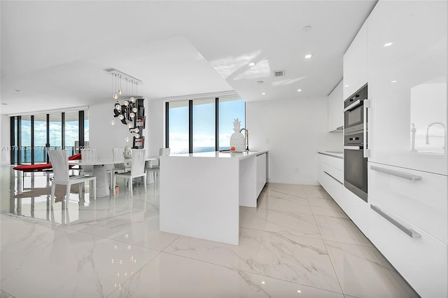 kitchen with white cabinetry, stainless steel oven, plenty of natural light, and pendant lighting