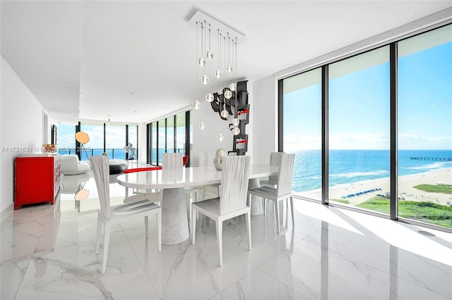 dining area featuring expansive windows, a water view, and a view of the beach