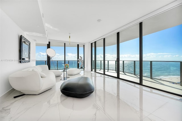 living room with a water view, a wall of windows, and a view of the beach