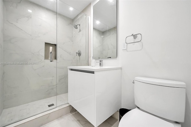 bathroom featuring vanity, a shower with door, and toilet