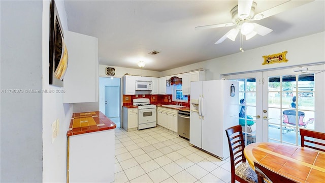 kitchen with tasteful backsplash, white cabinetry, sink, white appliances, and french doors