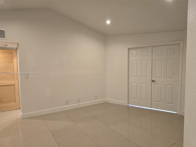 unfurnished bedroom with lofted ceiling, light tile patterned floors, and a closet