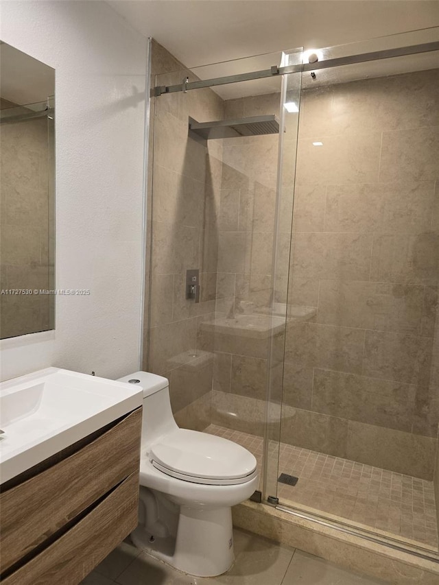 bathroom with tile patterned floors, vanity, toilet, and a shower with door