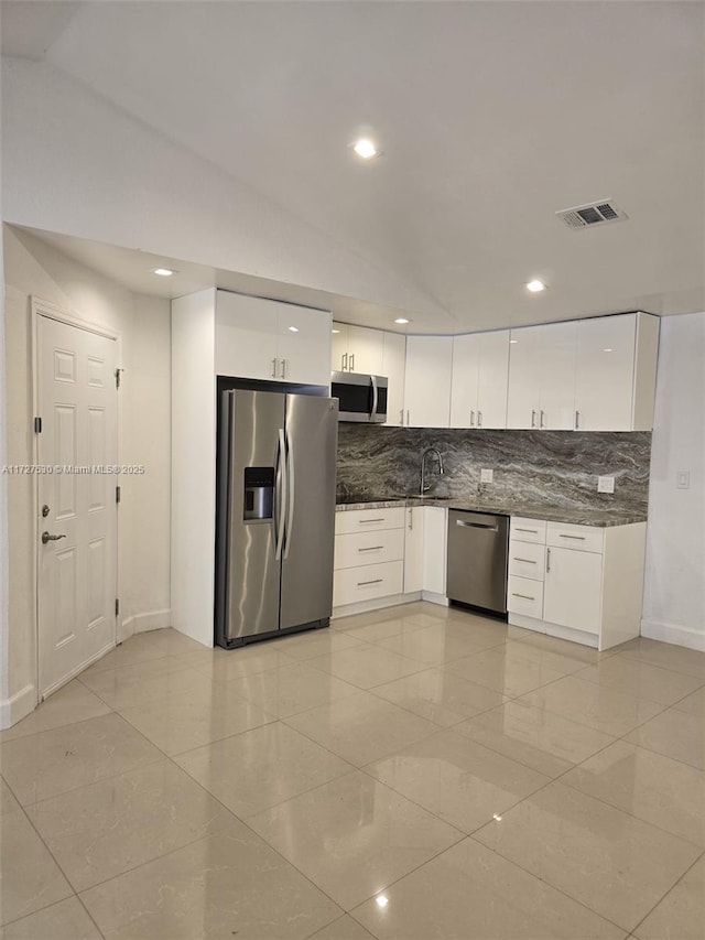 kitchen featuring backsplash, stainless steel appliances, vaulted ceiling, and white cabinets