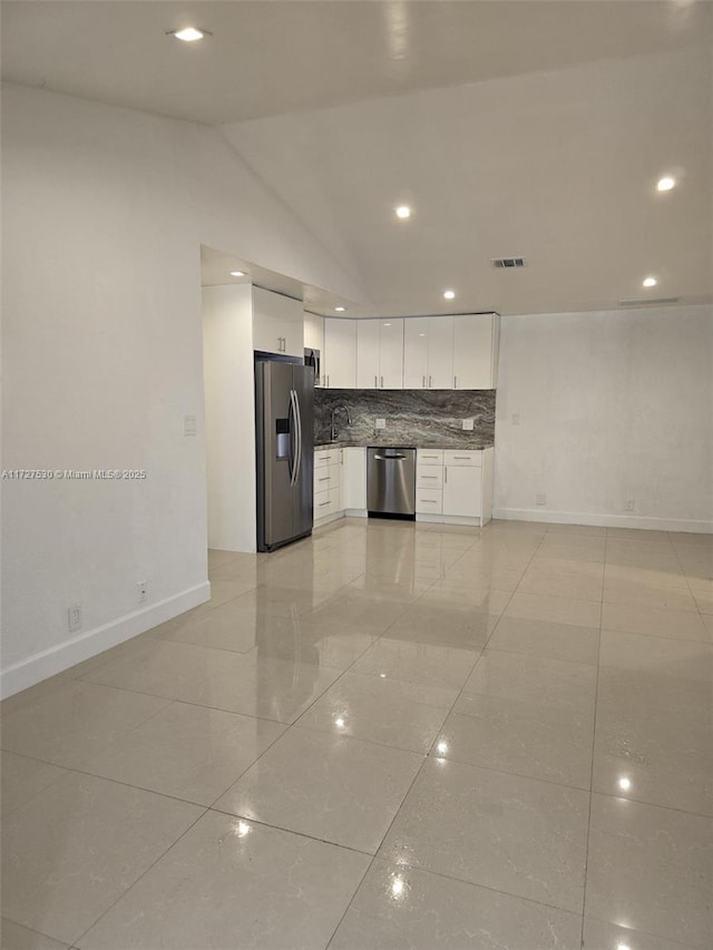 kitchen featuring stainless steel appliances, white cabinetry, vaulted ceiling, and backsplash