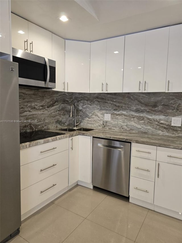 kitchen with light tile patterned flooring, appliances with stainless steel finishes, sink, and white cabinets