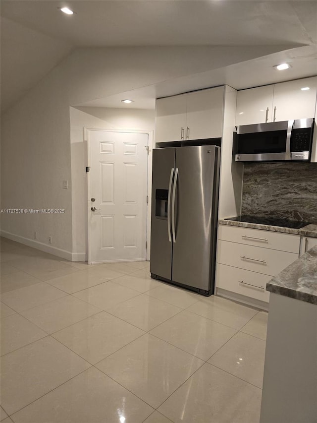 kitchen featuring white cabinetry, tasteful backsplash, vaulted ceiling, light tile patterned floors, and appliances with stainless steel finishes