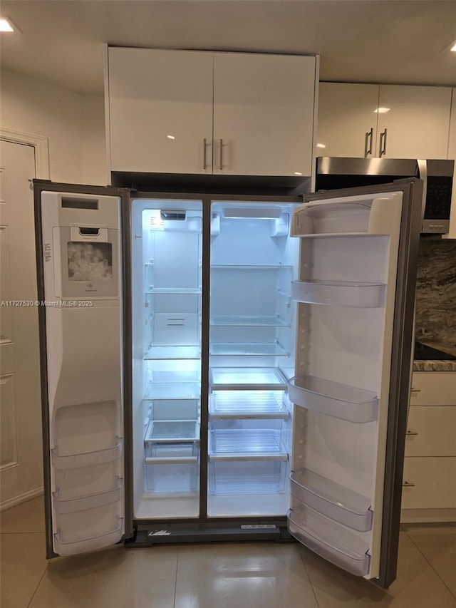 kitchen with tile patterned flooring, fridge, and white cabinets