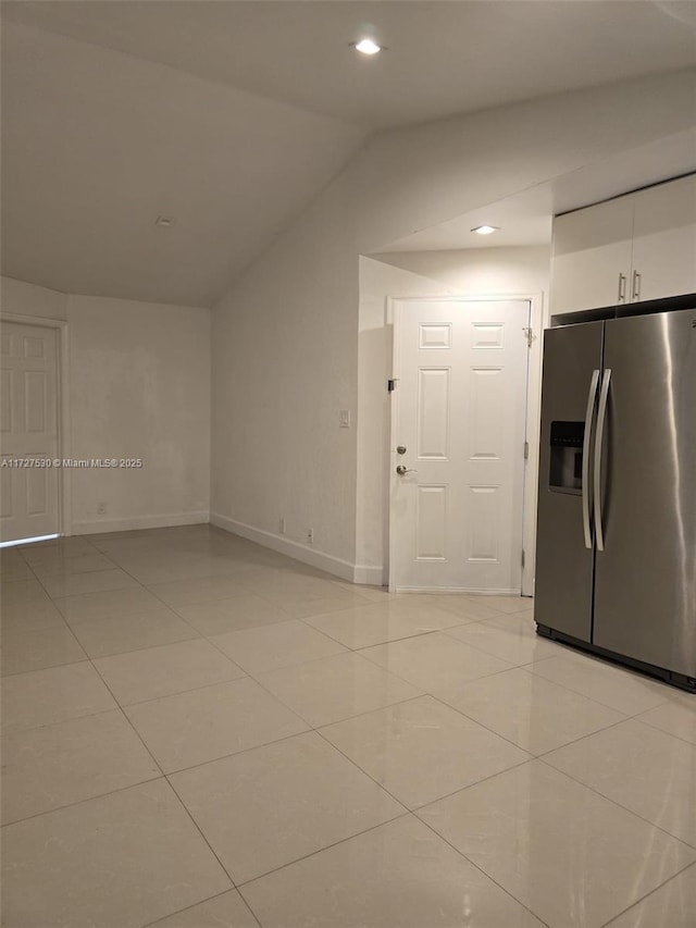 kitchen with vaulted ceiling, light tile patterned flooring, stainless steel fridge with ice dispenser, and white cabinets