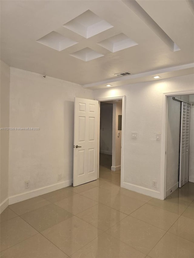 spare room featuring tile patterned flooring and coffered ceiling