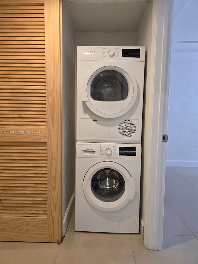 clothes washing area featuring stacked washer / drying machine and light tile patterned floors