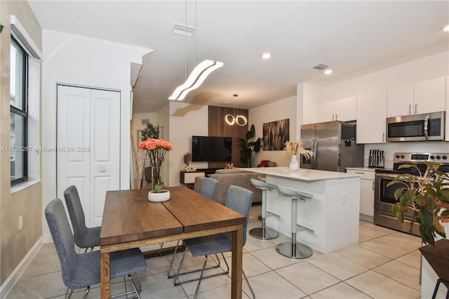 kitchen with a breakfast bar, white cabinetry, hanging light fixtures, a center island, and stainless steel appliances