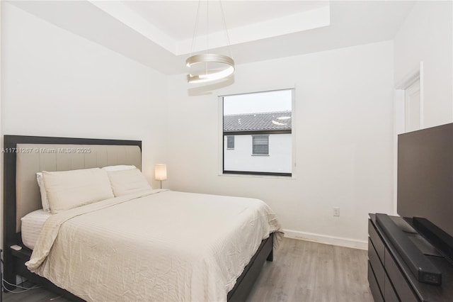 bedroom featuring light wood-type flooring and a tray ceiling