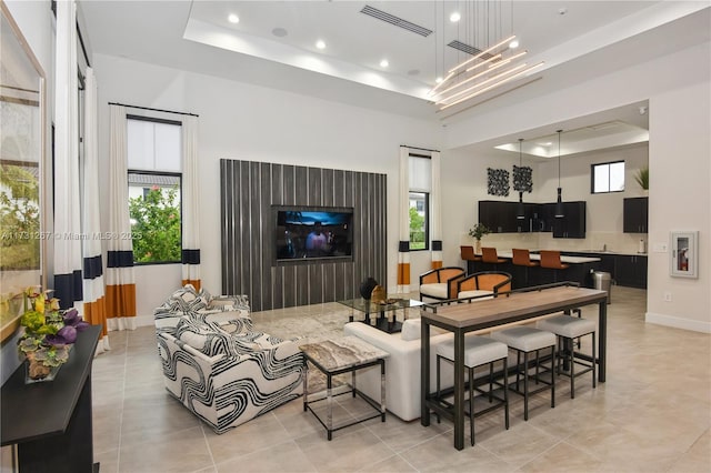 living room with a high ceiling, plenty of natural light, and a tray ceiling