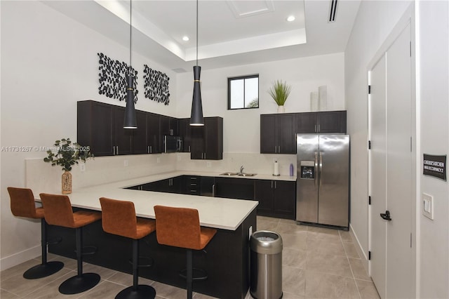 kitchen featuring a tray ceiling, pendant lighting, a breakfast bar area, kitchen peninsula, and stainless steel appliances