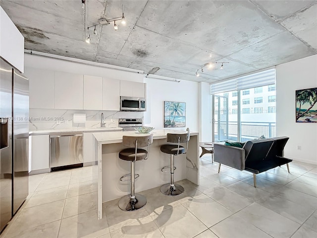 kitchen featuring sink, white cabinets, decorative backsplash, a center island, and stainless steel appliances