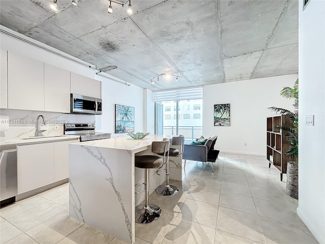 kitchen featuring sink, appliances with stainless steel finishes, track lighting, white cabinets, and a kitchen island