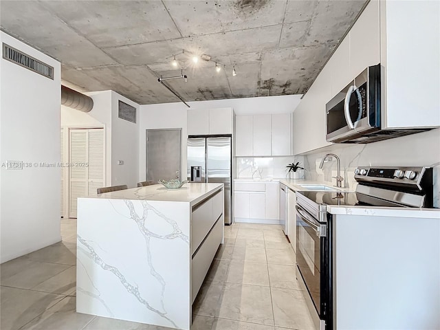 kitchen with sink, white cabinetry, tasteful backsplash, appliances with stainless steel finishes, and a kitchen island