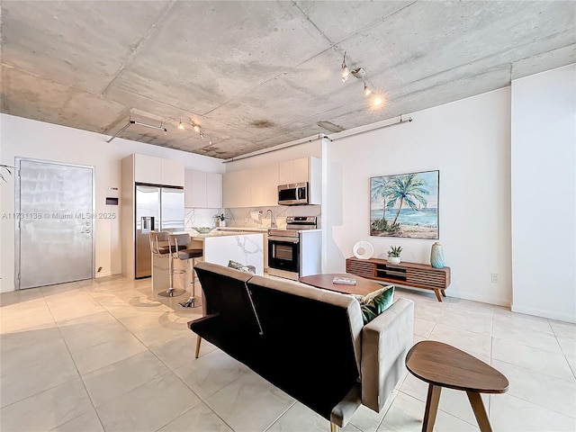 kitchen with a kitchen island, rail lighting, white cabinetry, a breakfast bar area, and stainless steel appliances