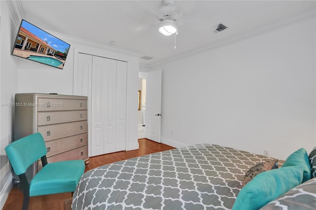 bedroom with hardwood / wood-style floors, ornamental molding, a closet, and ceiling fan