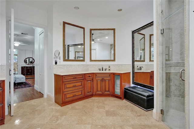 bathroom featuring ceiling fan, vanity, an enclosed shower, and decorative backsplash