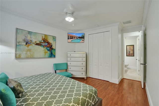 bedroom featuring crown molding, ceiling fan, wood-type flooring, and a closet