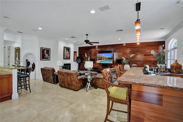 living room featuring ornamental molding, ceiling fan, and wood walls