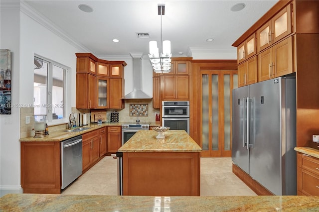 kitchen featuring light stone counters, a center island, pendant lighting, stainless steel appliances, and wall chimney range hood