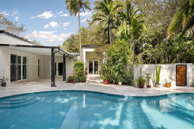 view of swimming pool featuring french doors, a fenced in pool, and a patio