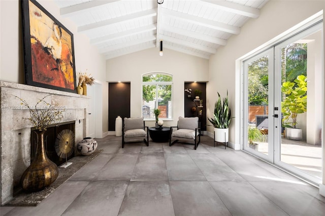 sitting room featuring french doors, concrete flooring, high vaulted ceiling, beamed ceiling, and a tiled fireplace