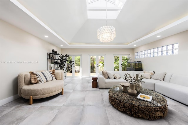 living room with an inviting chandelier, french doors, a raised ceiling, and a high ceiling