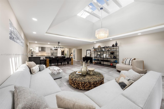 living room featuring a tray ceiling, a skylight, and a notable chandelier