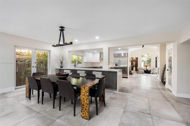 dining space featuring a notable chandelier, sink, vaulted ceiling, and french doors