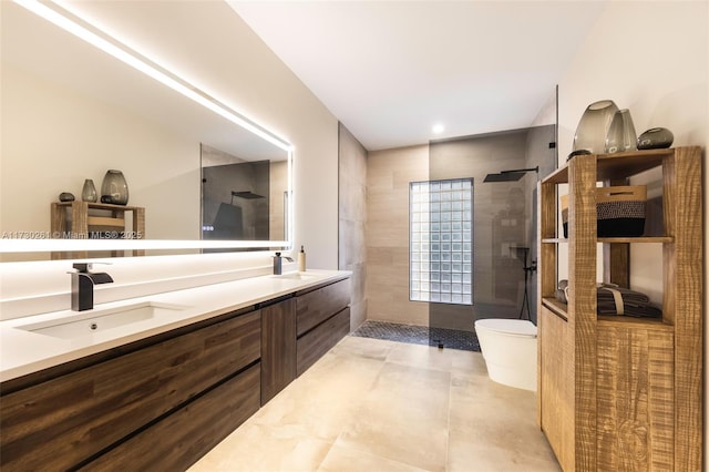 bathroom with vanity, tiled shower, and toilet