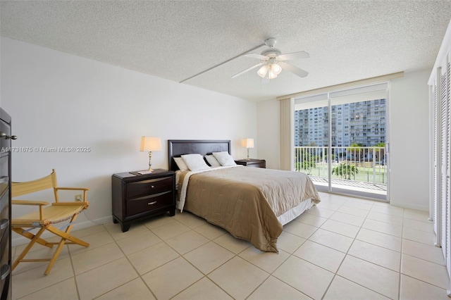 bedroom with ceiling fan, access to exterior, expansive windows, a textured ceiling, and light tile patterned flooring