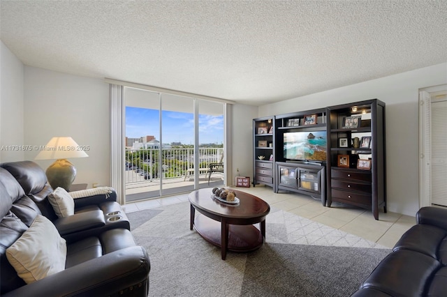 living room with light tile patterned flooring, a wall of windows, and a textured ceiling