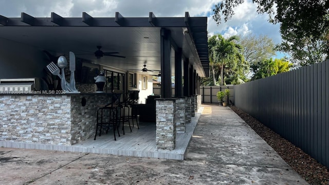 view of patio featuring ceiling fan and a bar