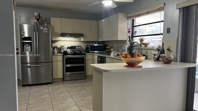 kitchen featuring light tile patterned flooring, a textured ceiling, kitchen peninsula, ceiling fan, and stainless steel appliances