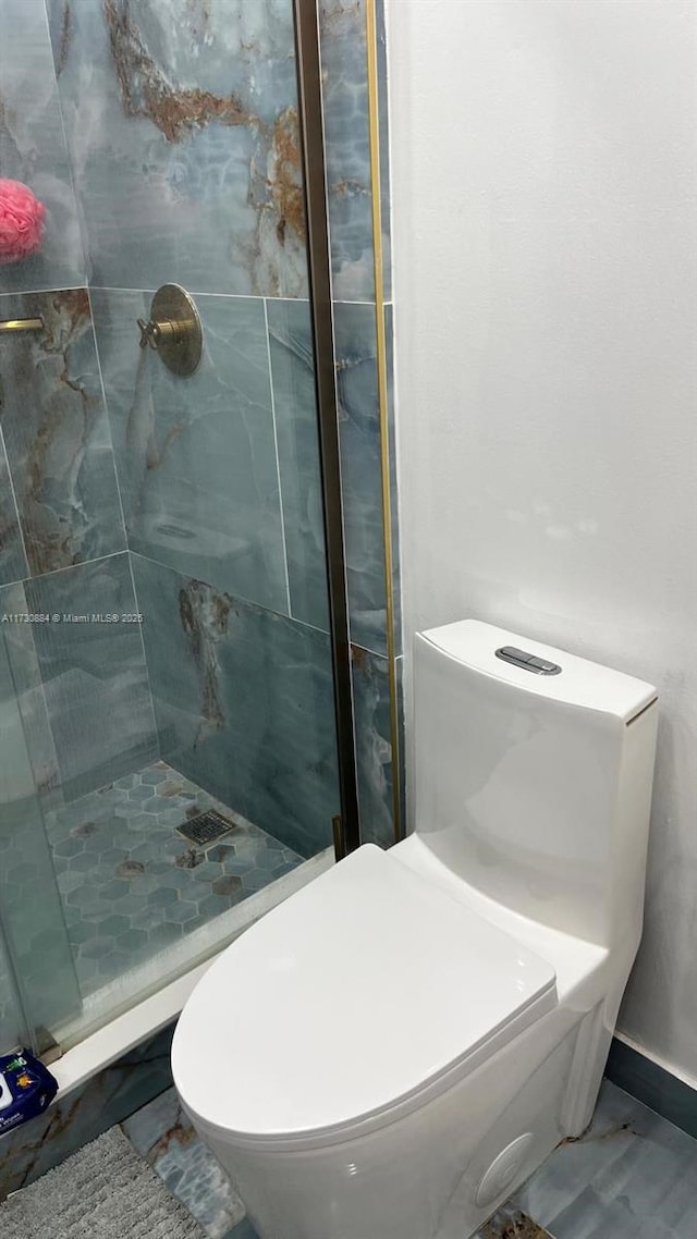 bathroom featuring tiled shower and toilet