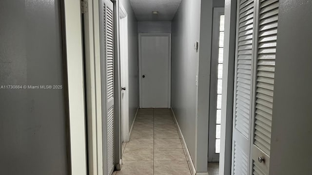 hall with light tile patterned floors and a textured ceiling