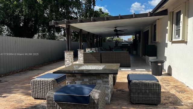 view of patio / terrace with ceiling fan and an outdoor living space with a fire pit