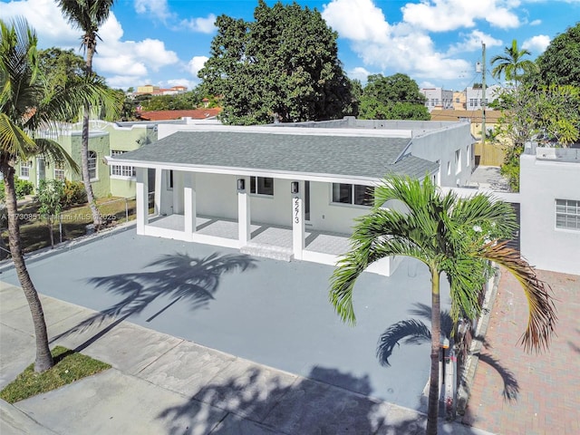 exterior space featuring roof with shingles, fence, and stucco siding