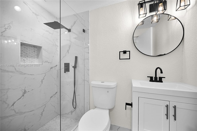 bathroom featuring toilet, a textured wall, a marble finish shower, and vanity