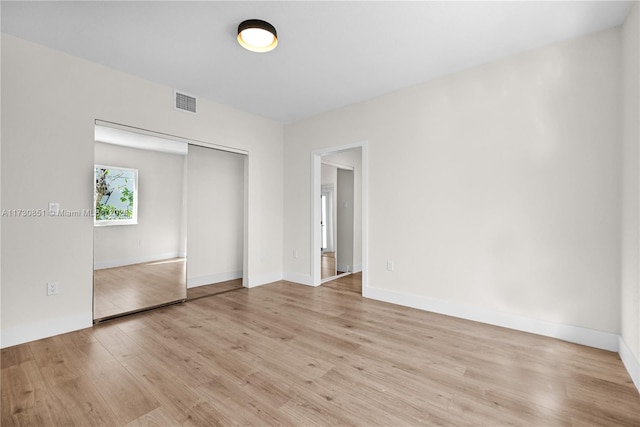 unfurnished bedroom featuring a closet, baseboards, visible vents, and light wood finished floors