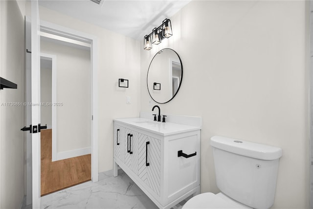 bathroom with marble finish floor, vanity, toilet, and baseboards