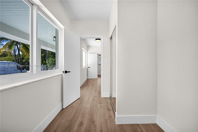 corridor featuring baseboards and wood finished floors