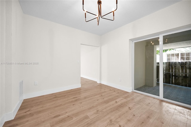 unfurnished room featuring a chandelier, visible vents, baseboards, and wood finished floors