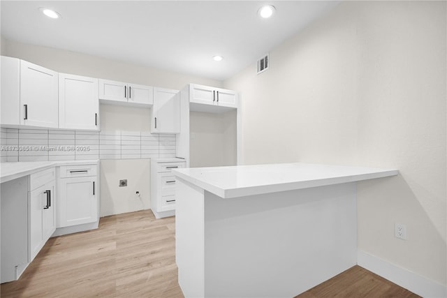 kitchen with a peninsula, light wood-style flooring, and white cabinets