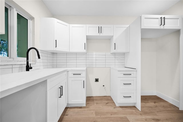 kitchen featuring light wood-type flooring, tasteful backsplash, and white cabinetry